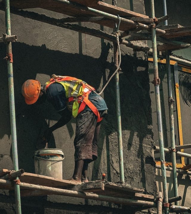A construction worker applies plaster on a building facade in Abuja, Nigeria.
